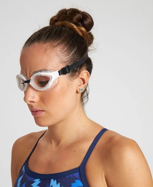 Swimmer holding Arena Air Bold Swipe goggles – lightweight anti-fog swim gear for open water and triathlon.