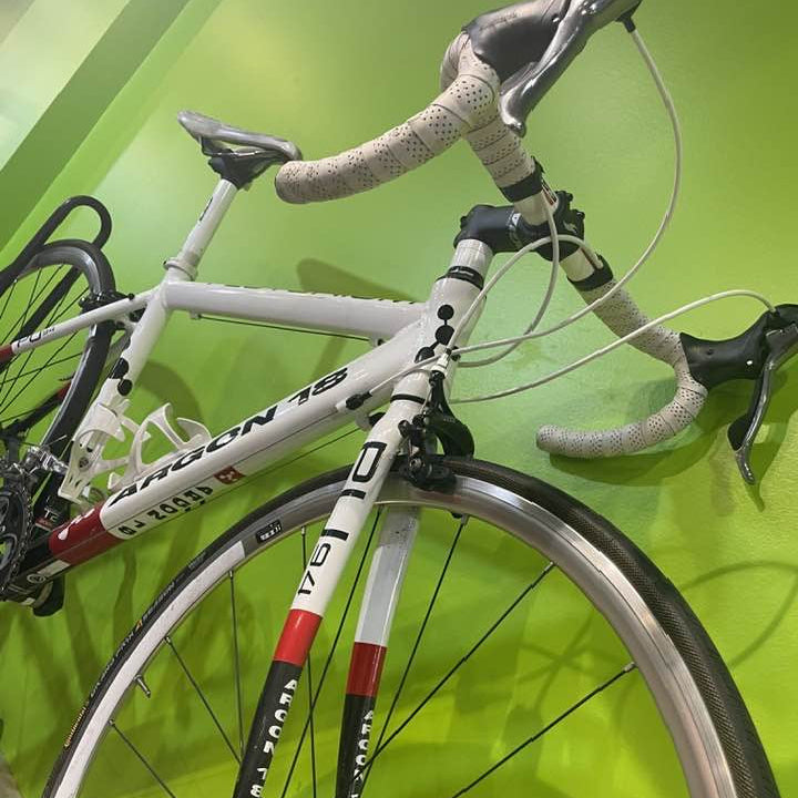 White bicycle with black and red details against a green wall
